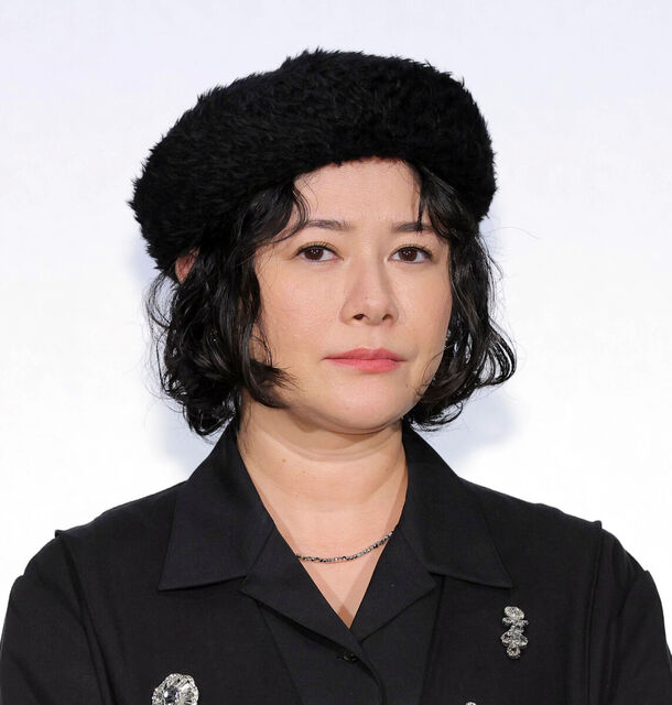 黒い帽子と黒い服を身につけた女性が正面を見ている画像です。