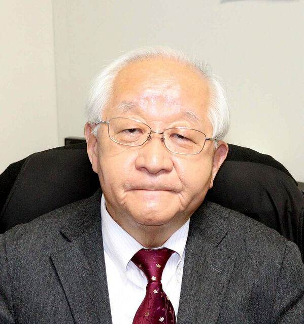 "メガネをかけてスーツを着用し、穏やかな表情で椅子に座っている政治評論家・田崎史郎氏のポートレート写真。"