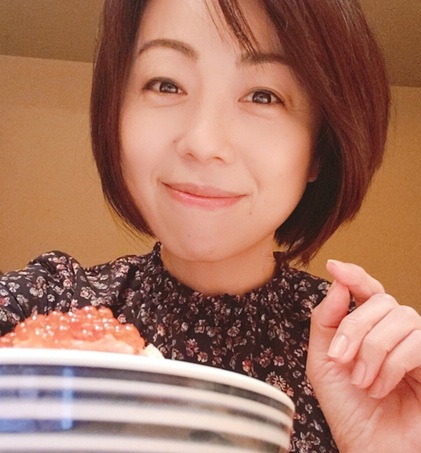 "料理を手に持ち、優しい笑顔でカメラを見つめている女性"