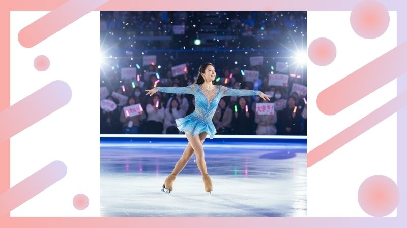 　- アイスリンクでパフォーマンスを披露し、観客から喝采を浴びる日本人フィギュアスケーターの女性。紙吹雪が舞い、観客はペンライトを振っている。