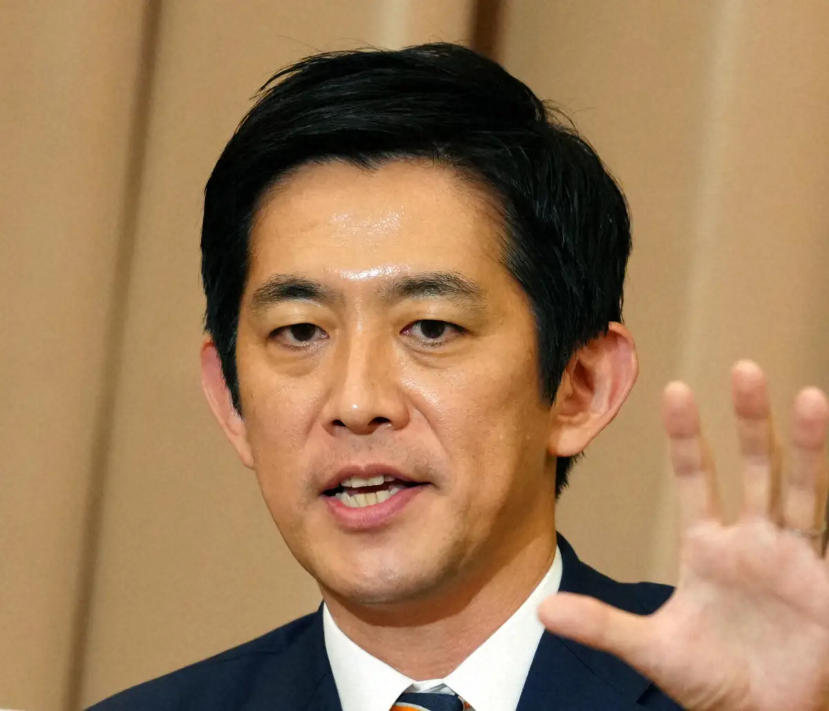 スーツ姿で右手を挙げて話す小林鷹之氏