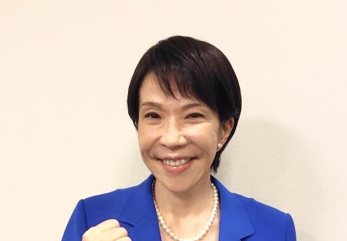 青いスーツを着て笑顔でガッツポーズをする高市早苗氏