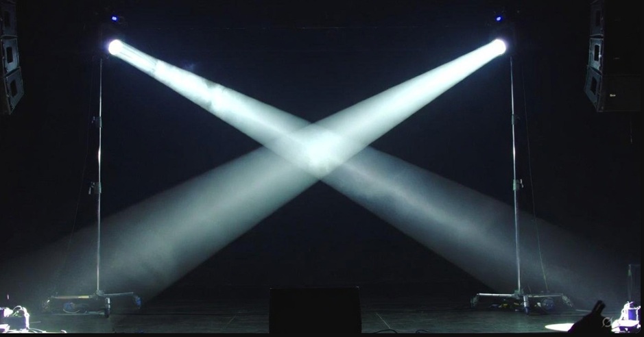 暗いステージ上で交差する2つのスポットライト。別々の道を歩みながらも根底で繋がっている二人の絆を象徴